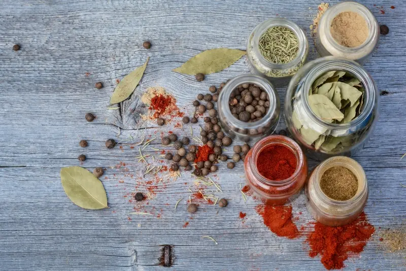 Small jars of colorful ground spices and dried herbs on a table