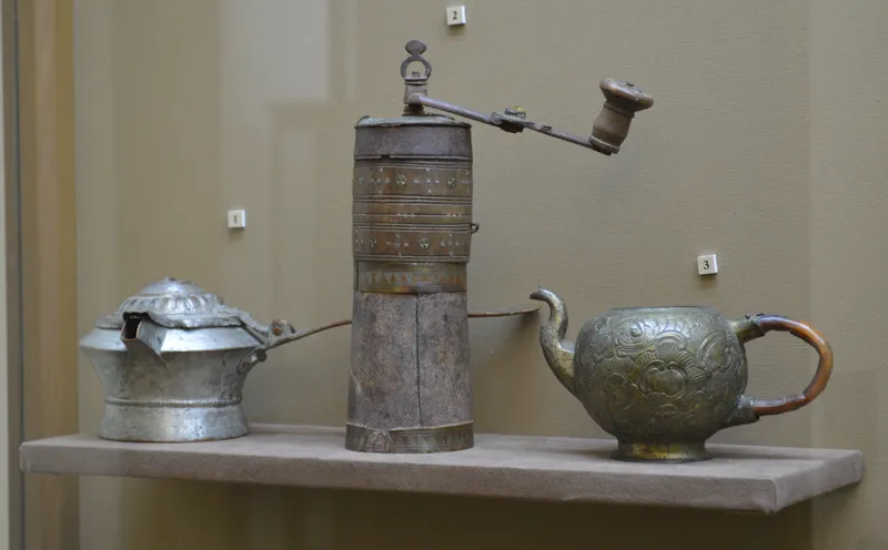 A vintage spice grinder on a kitchen shelf
