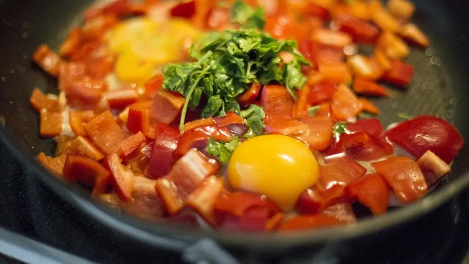 A colorful skillet of shakshuka with eggs and herbs